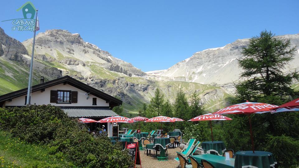 Terrasse de la cabane et parasols rouges au pied des montagnes